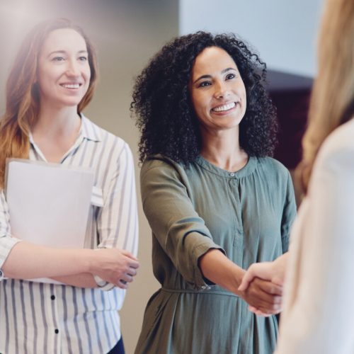 Cropped shot of two young businesswomen shaking hands during a meeting in the boardroom.