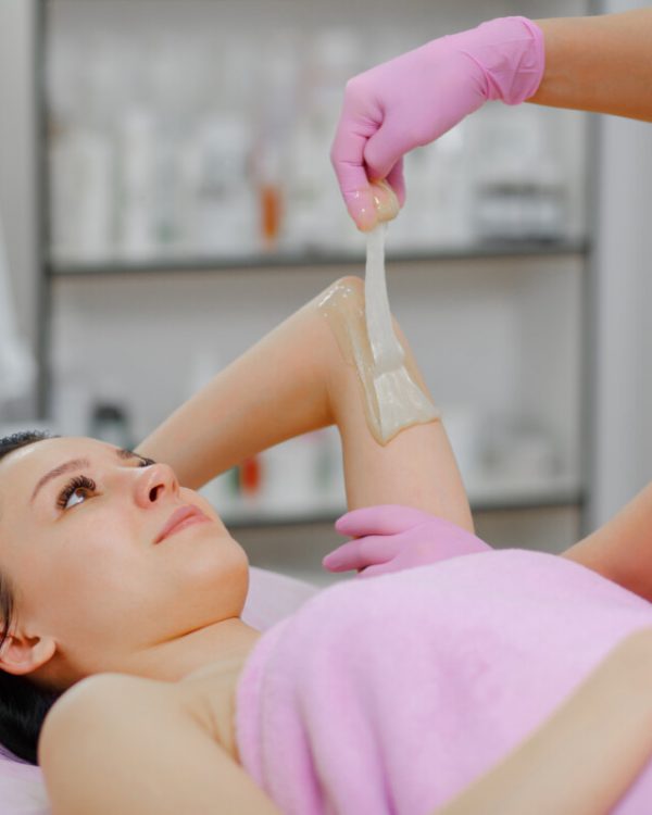 Sugaring: Beauty Concept. Young beautiful girl with dark hair gets the procedure for hair removal liquid sugar